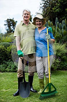 Portrait of senior couple standing with garden tools