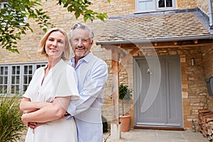 Portrait Of Senior Couple Standing Outside Front Door Of Home