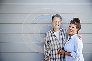 Portrait Of Senior Couple Standing Outside Grey Clapboard House