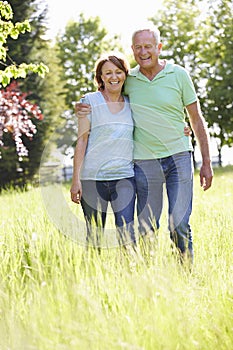 Portrait Of Senior Couple Walking In Summer Countryside