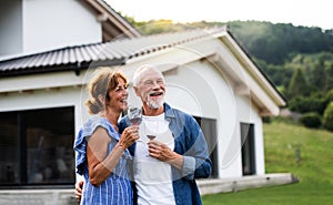 Portrait of senior couple with wine outdoors in backyard.