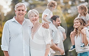 Portrait senior couple and young family members outside in the garden. Happy smiling parents relaxing outside with their