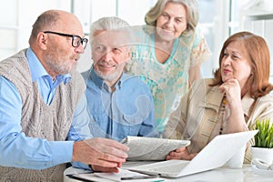 Portrait of senior couples working with laptop and reading newspaper