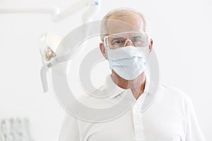 Portrait of senior dentist wearing mask and glasses at dental clinic