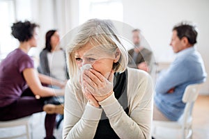 A portrait of senior depressed woman crying during group therapy.