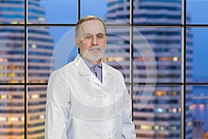 Portrait of senior doctor with night cityscape background.