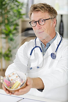 Portrait senior doctor offering bunch pills