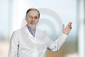 Portrait of senior doctor pointing up showing on copy space.