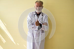 Portrait of senior doctor standing and showing thumb up at hospital,Happy and smiling positive thinking attitude