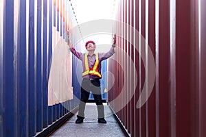 Portrait of senior elderly Asian worker engineer wearing safety vest and helmet, raising hand up, standing between red and blue
