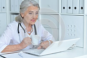 Portrait of senior female doctor drinking tea