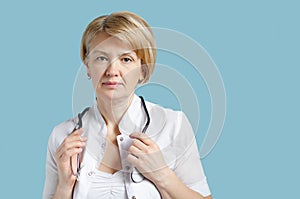 Portrait of senior female doctor with stethoscope in his hands on blue background