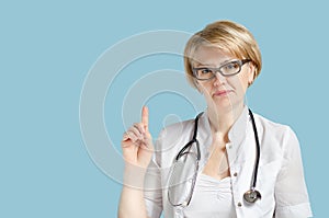 Portrait of senior female doctor with stethoscope show pointing attention finger gesture.