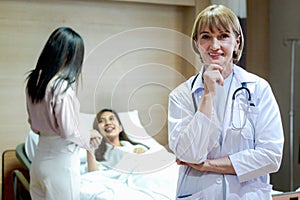 Portrait of senior female doctor in workwear with stethoscope standing and thinking and taking decisions with hand on chin in