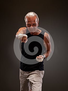 Portrait of a senior fighter punching towards camera