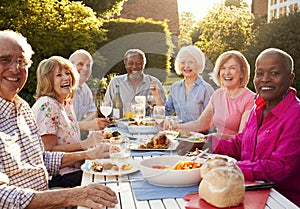 Portrait Of Senior Friends Enjoying Outdoor Dinner Party At Home