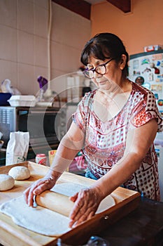 Portrait of an senior hispanic woman cooking homemade bread in her kitchen