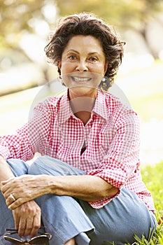 Portrait Of Senior Hispanic Woman Sitting In Park