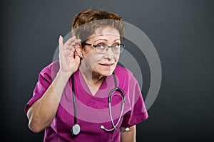 Portrait of senior lady doctor showing can`t hear gesture