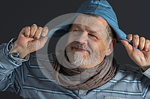 Portrait of senior man in blue shirt and cap being happy like a kid