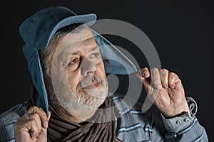 Portrait of senior man in blue shirt and kids cap dreaming like in childhood