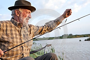 Portrait Of Senior Man On Camping Holiday With Fishing Rod, Alone Outdoors In Nature