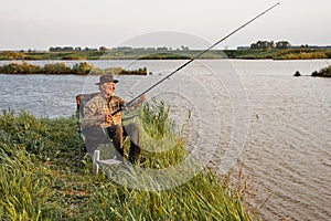 Portrait Of Senior Man On Camping Holiday With Fishing Rod, Alone Outdoors In Nature