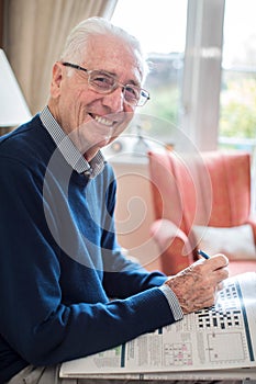 Portrait Of Senior Man Doing Crossword Puzzle At Home