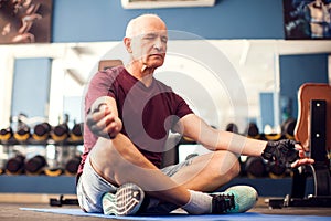 A portrait of senior man doing relaxation exercise in the gym. People, healthcare and lifestyle concept