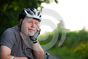 Portrait of senior man enjoying summer cycling in the forest during lovely sunset, active pensioner