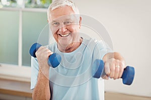 Portrait of senior man exercising with dumbbells