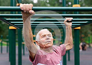 Portrait of senior man exercising on simulators on sports ground