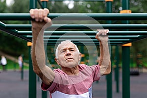 Portrait of senior man exercising on simulators on sports ground