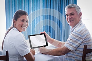 Portrait of senior man and female doctor using digital tablet