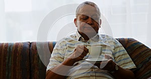 Portrait of senior man having coffee on sofa 4k