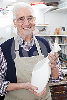 Portrait Of Senior Man Holding Vase In Pottery Studio