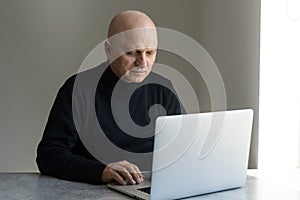 Portrait of senior man at home working on laptop