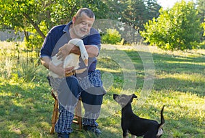 Portrait of senior man introducing black puppy to his cute friend white goose