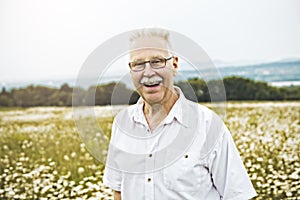 Portrait senior man outdoors in a daisy field