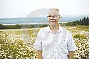 Portrait senior man outdoors in a daisy field