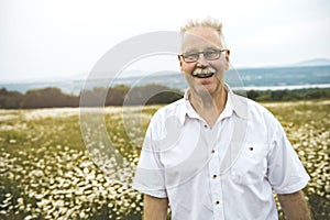 Portrait senior man outdoors in a daisy field