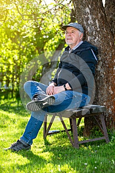 Portrait of a senior man outdoors, sitting on a bench in a park, optimism, good health, expression, retirement or