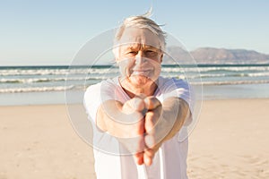 Portrait of senior man practicing yoga at beach