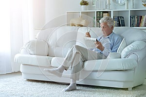 Portrait of senior man reading newspaper at home