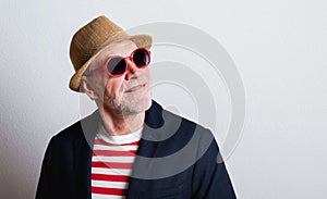 Portrait of a senior man with red sunglasses in a studio.