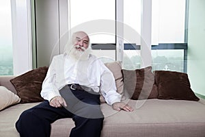 Portrait of senior man relaxing on sofa in apartment