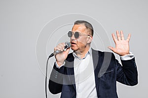 Portrait of a senior man singing into microphone isolated on white background