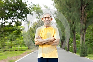 portrait senior man standing crossed arms on the street in the park