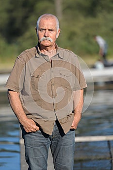 Portrait senior man standing by water