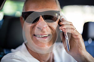 Portrait of senior man talking on phone in car